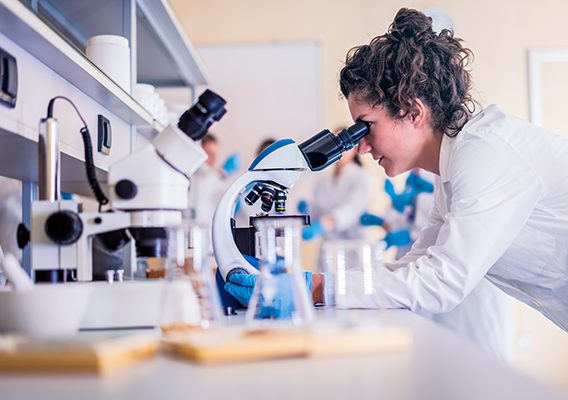 Scientist in lab doing research and using lab machines, test tubes, microscope and every laboratory equipment